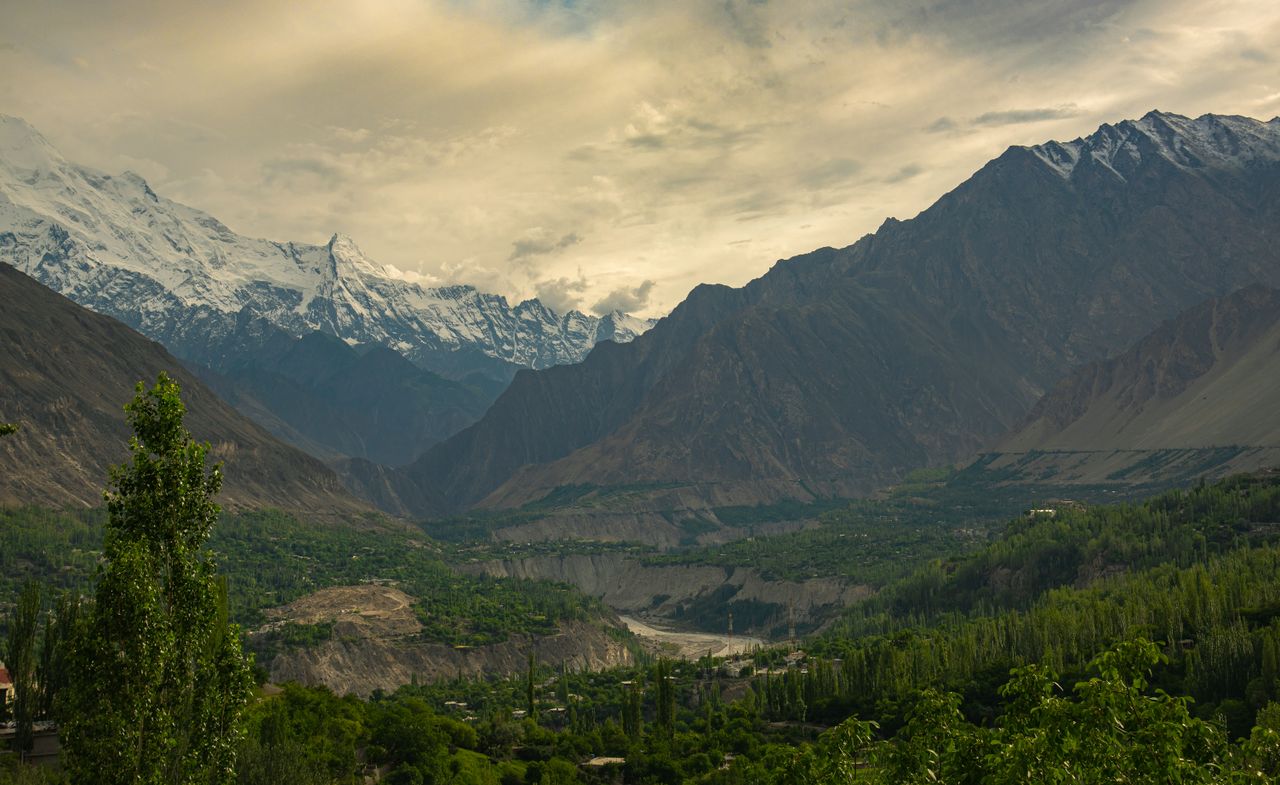 Home Breathtaking view of Hunza Valley with lush greenery and snow-capped peaks.